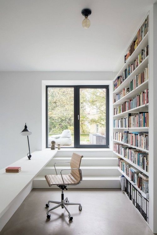 Ljust, minimalistiskt arbetsrum med skrivbord, stol och bokhylla