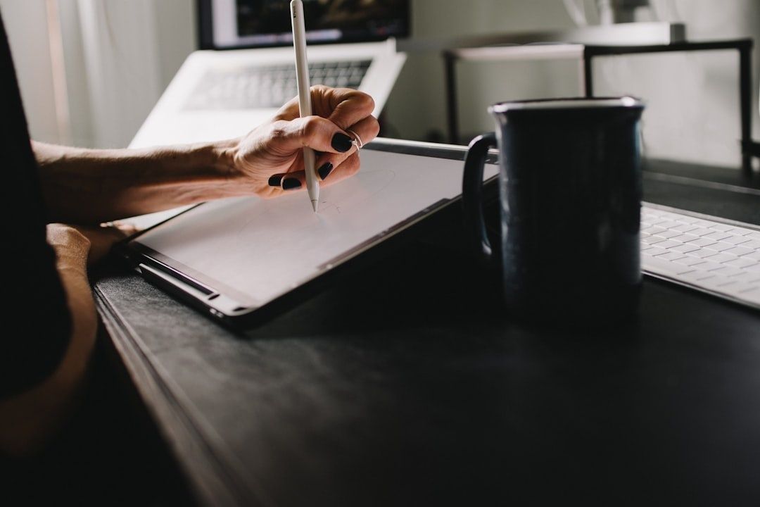Person studerar vid skrivbord med penna, ritplatta och kaffemugg