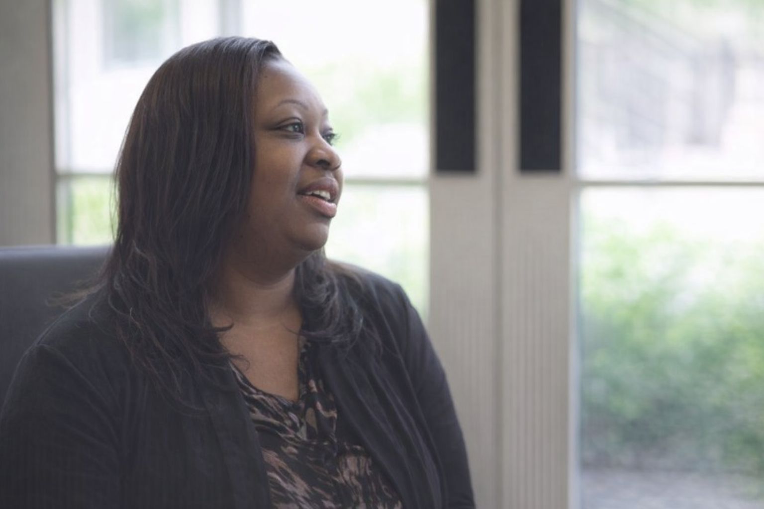 Kvinna som ser glad ut i en ljus kontorsmiljö eller skolmiljö.